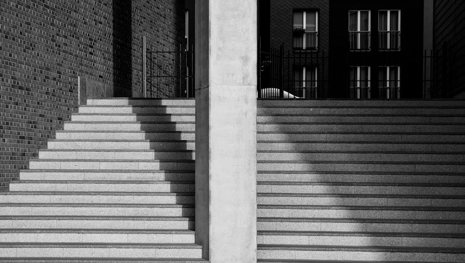 A person appears to be struggling to navigate the staircase on a Harringay terrace with narrow, steep steps made of concrete. They are outside a building and are holding onto a metal railing for suppo